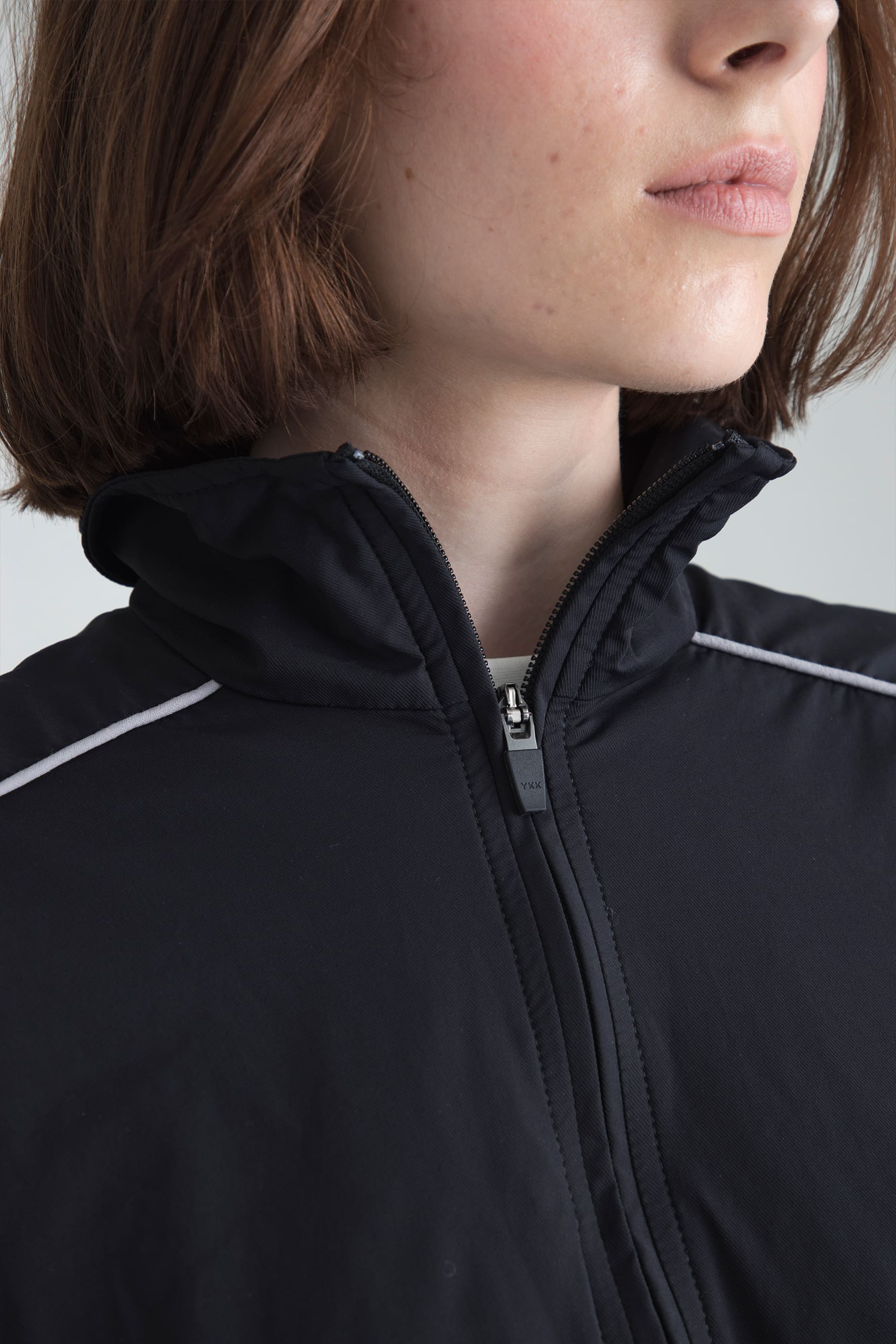 Detail of high neck and closure on Women's black jacket